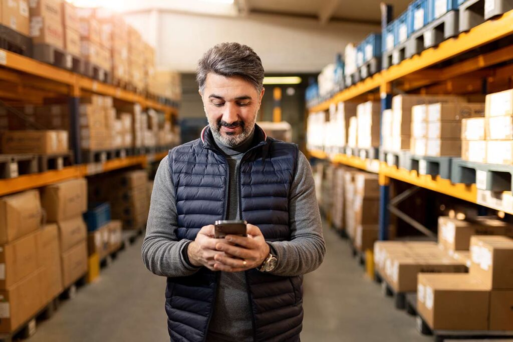 male warehouse business owner using mobile device