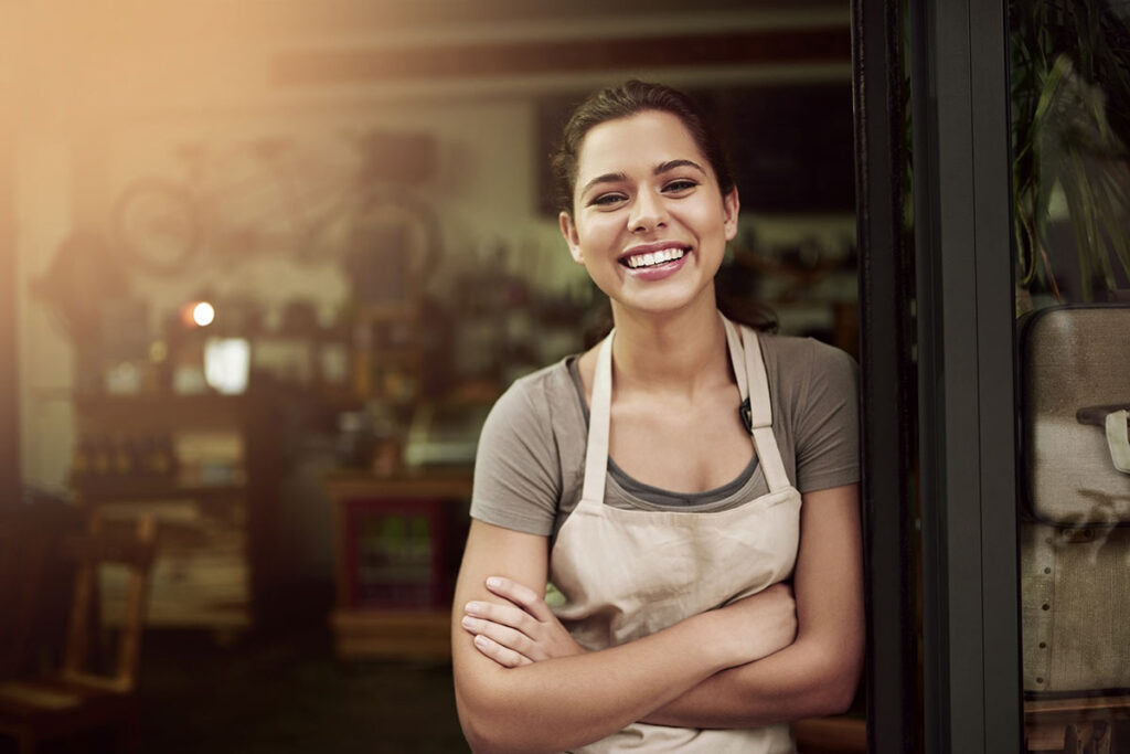 female coffee shop owner smiling at entrance to cafe, unsecured business line of credit